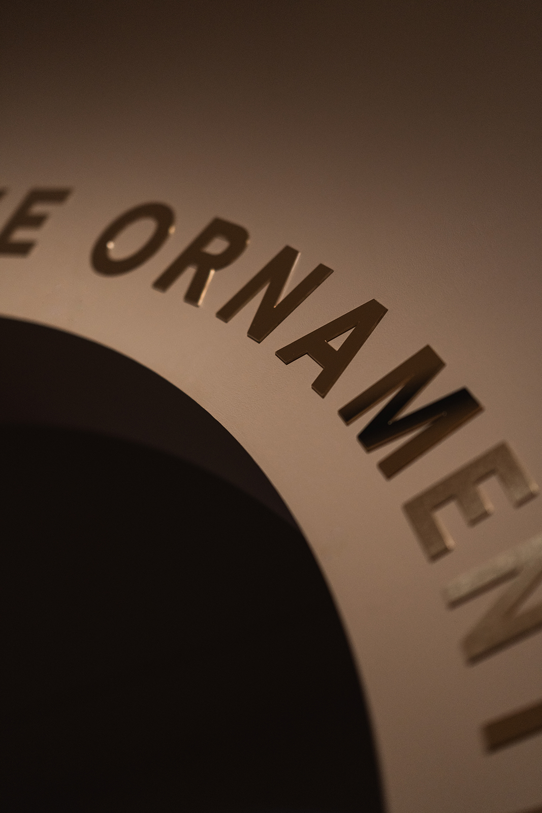 Ekstremt nærbilde av utstanset eller påført typografi på en buet flate, som viser skyggevirkning og materialitet.