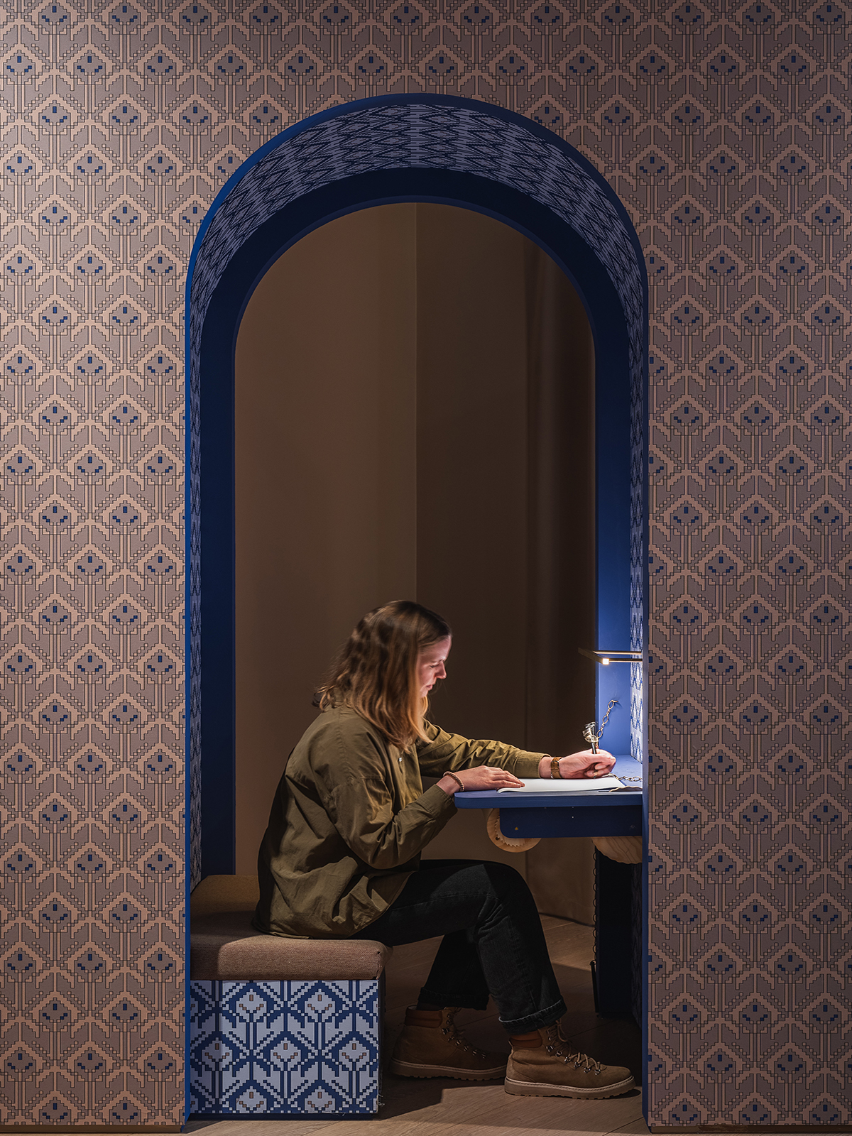 Detaljbilde av en person i aktivitet ved en innebygd arbeidsstasjon, omkranset av det karakteristiske blå mønsteret.