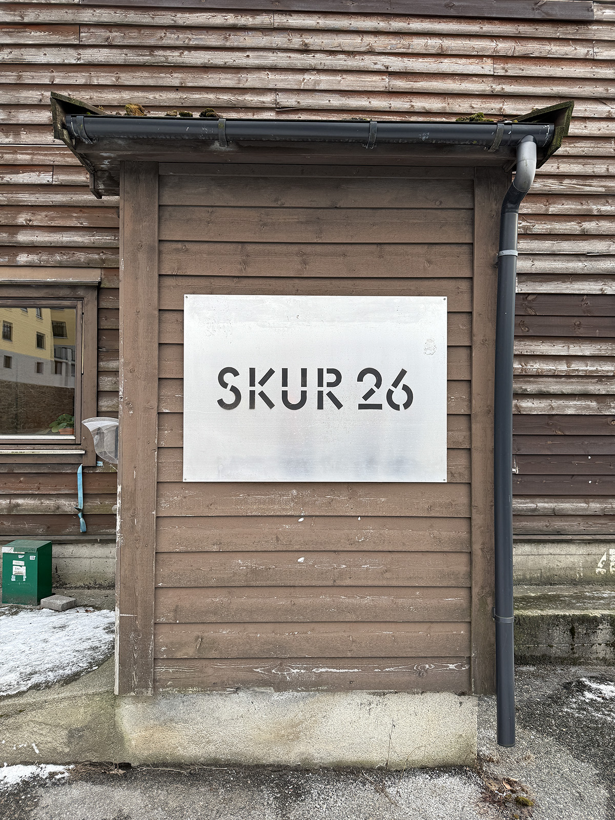 Skiltet til ombrukshallen Skur 26 montert på en trekledd fasade